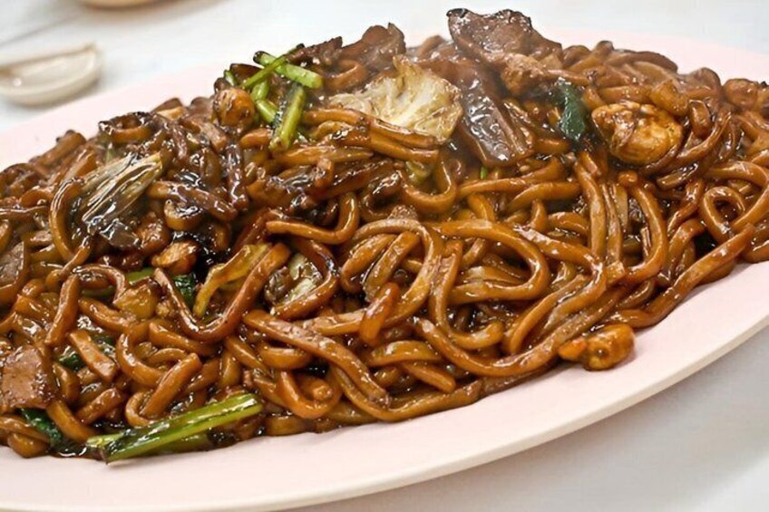A plate of stir-fried noodles with vegetables and meat. 4