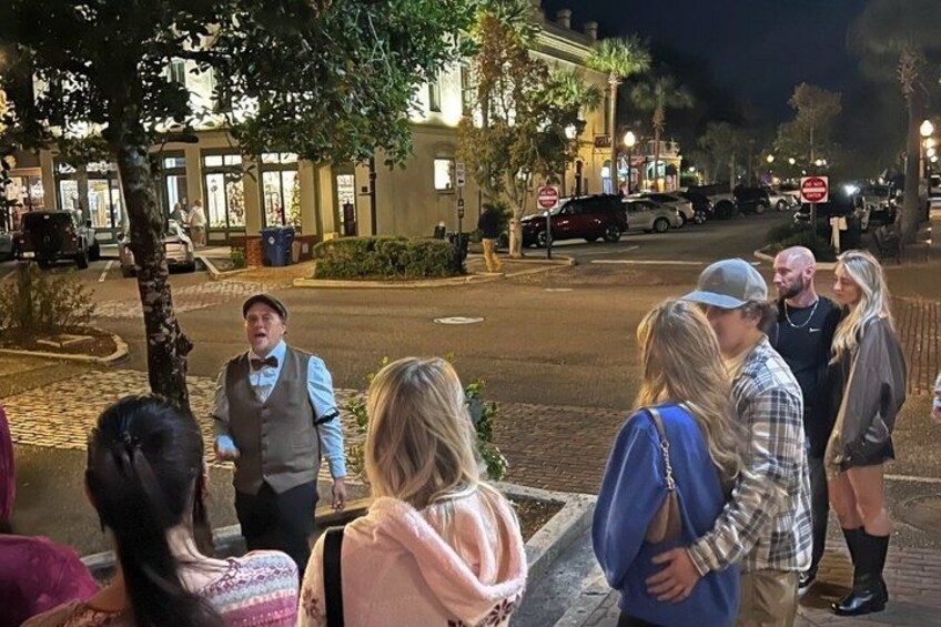 A group of people standing on a sidewalk at night. 2
