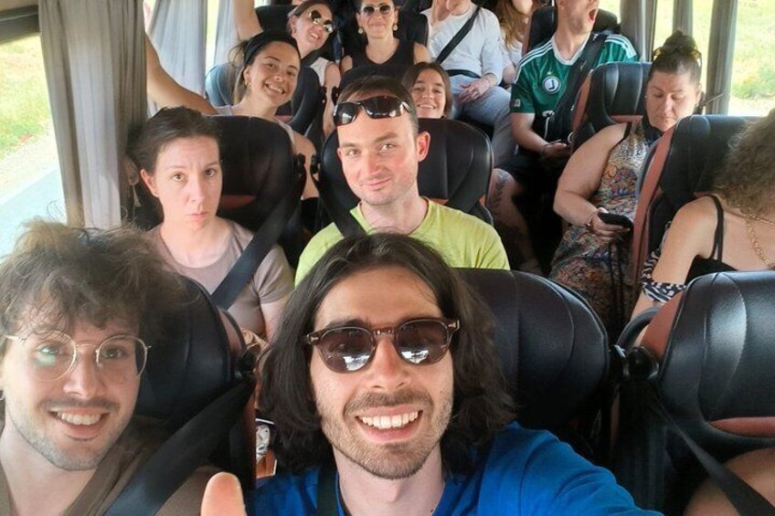 A group of people seated inside a vehicle, likely a bus, with windows and a door visible. 3
