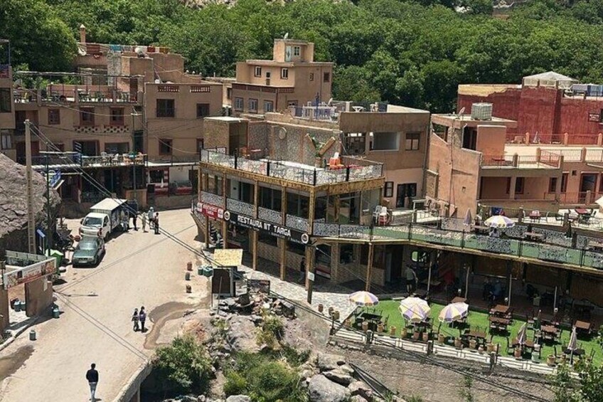 A street with buildings, a restaurant, and outdoor seating. 1