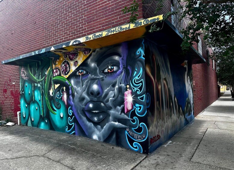 A vibrant mural on a red brick wall with a sign that reads 'Be Good Feel Good.' 5