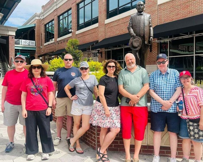 A group of people standing in front of a building with a statue and a sign that reads 'skins.' 1