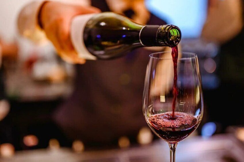A bottle of red wine being poured into a glass. 2