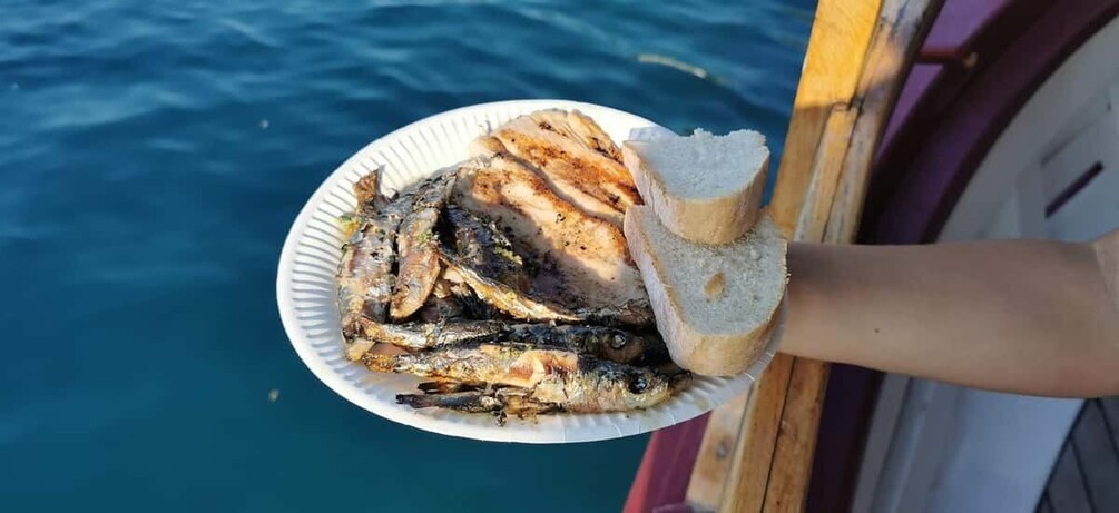 A plate of grilled fish and bread on a boat. 4
