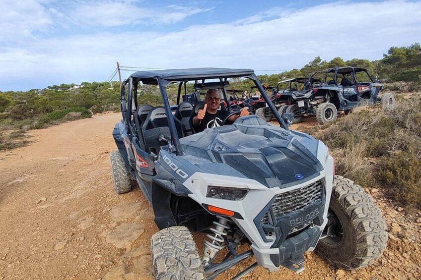 A white off-road vehicle with large tires on a dirt path. 3