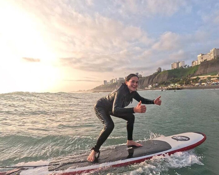 A person surfing on a wave with a cityscape in the background. 3