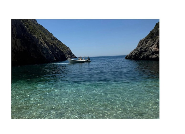 A boat on clear turquoise water between rocky cliffs. 2