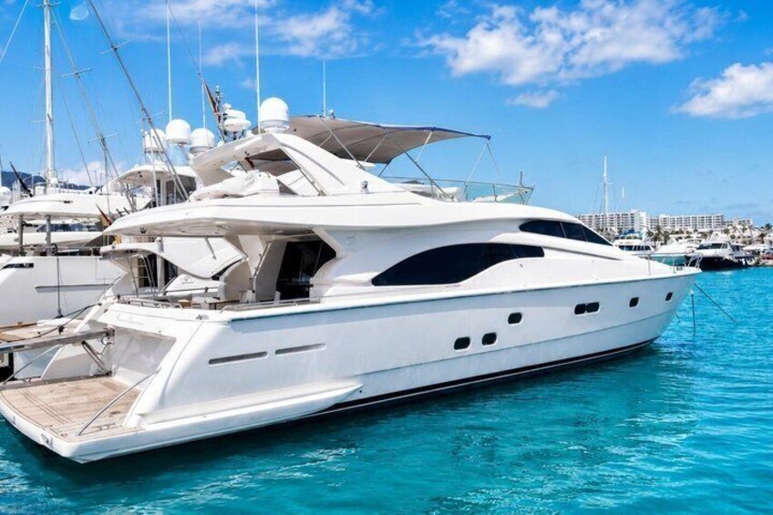 A white yacht docked at a marina with other boats in the background. 1
