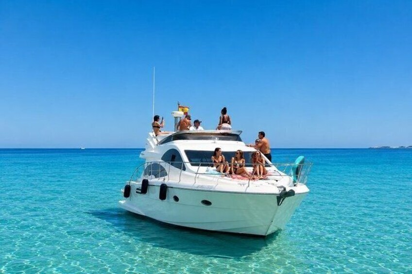 A white yacht with people on deck, floating on clear turquoise water. 5