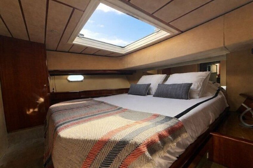 A bedroom with a skylight, a bed with patterned bedding, and wooden furniture. 2