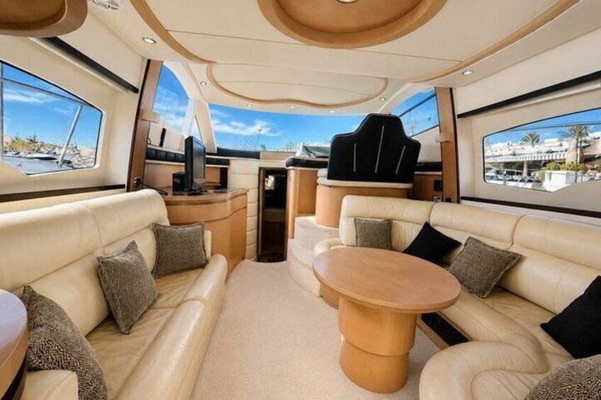 A yacht interior with leather sofas, a wooden table, and a TV. 3