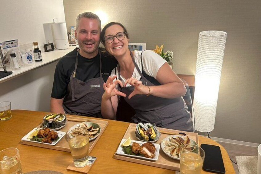 Two people sitting at a table with various dishes and drinks. 1
