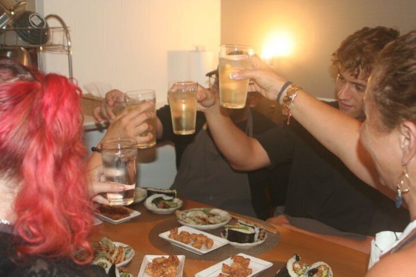 People toasting with drinks at a table with food. 1