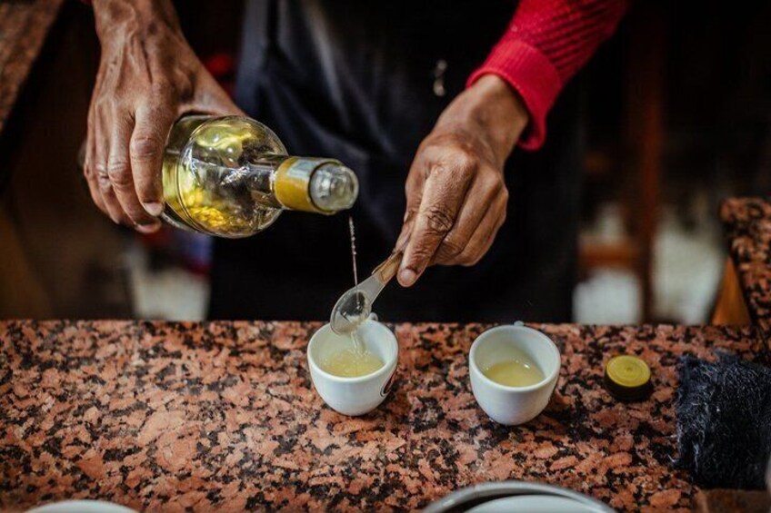A person pouring a liquid from a bottle into two small white bowls on a granite countertop. 2