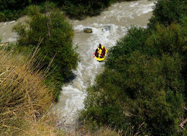 A group of people rafting down a river surrounded by dense greenery. 1