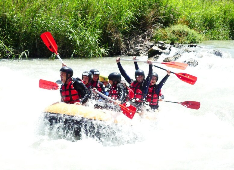 A group of people in a raft navigating a river with rapids. 2