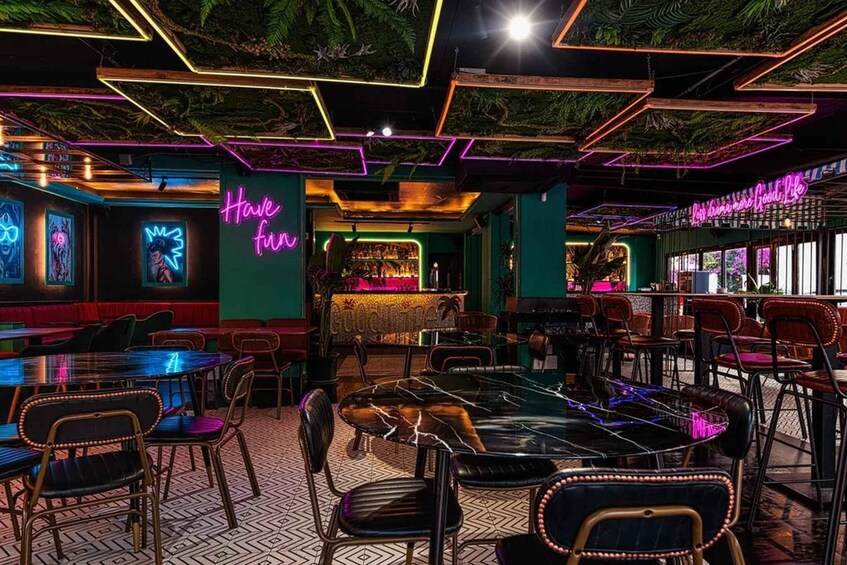 A neon-lit bar with a green wall and a neon sign that says 'Have fun.' 4