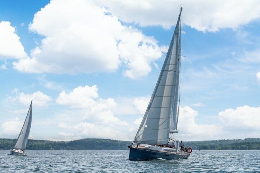 Two sailboats on a calm lake with a clear sky and distant hills. 4