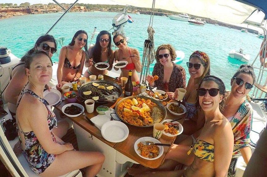 A group of people on a boat with a table full of food and drinks. 2