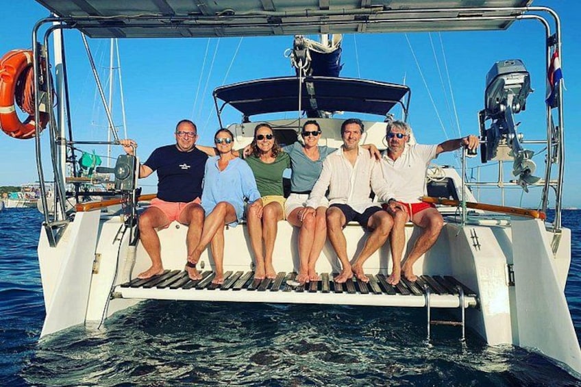 A group of people on a boat with a lifebuoy and a motor on the deck. 2
