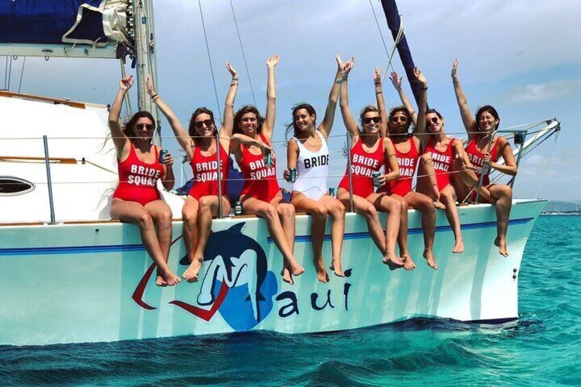A group of people on a boat with 'BRIDE SQUAD' written on their swimsuits. 5