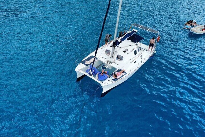 A sailboat with passengers on a clear blue sea. 1