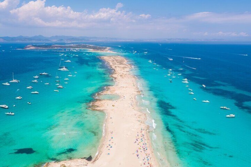 A beach with clear turquoise waters, a sandy shore, and numerous boats anchored nearby. 3