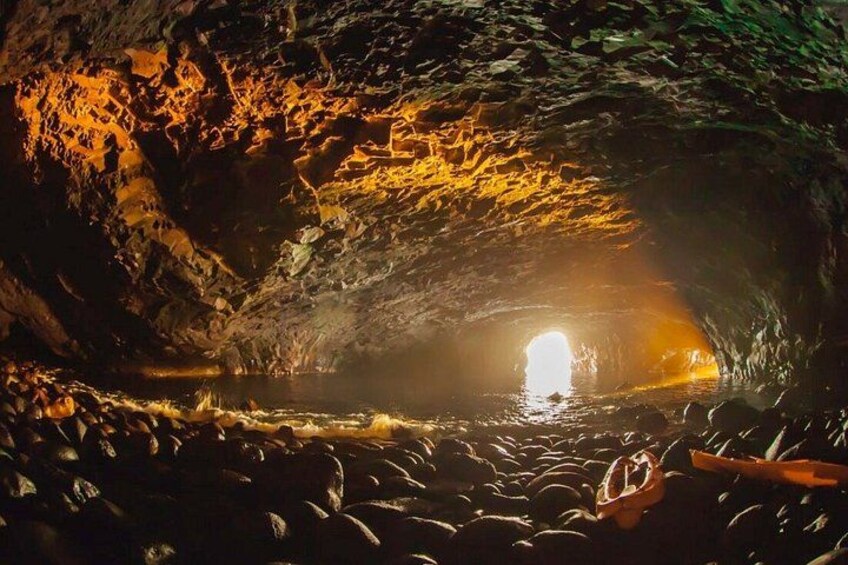 A cave with a water stream and a light source at the end. 2