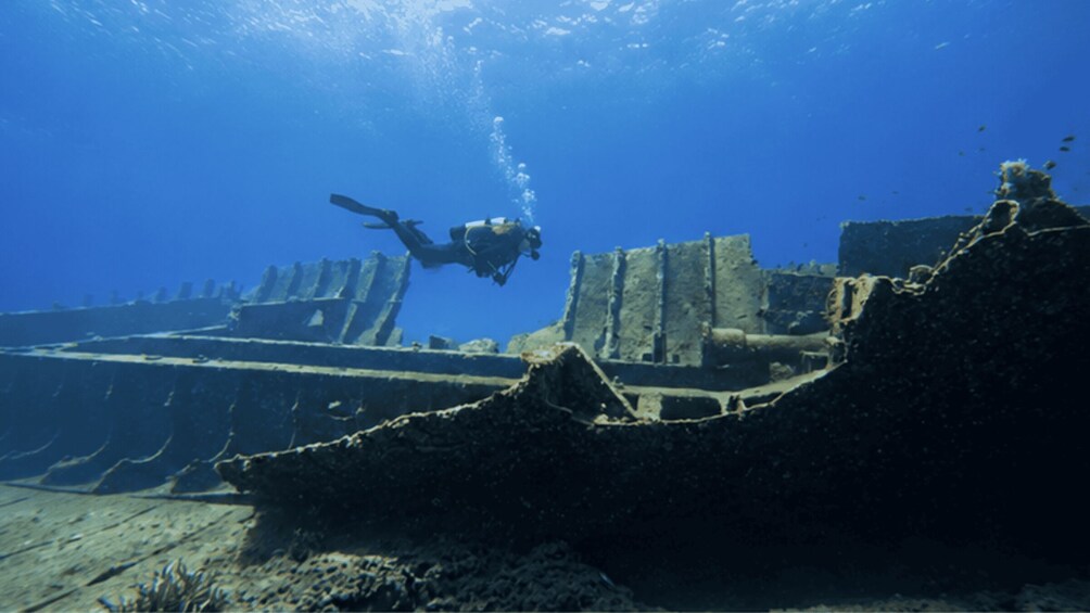 A diver exploring underwater ruins with coral formations and a diver's fins. 1