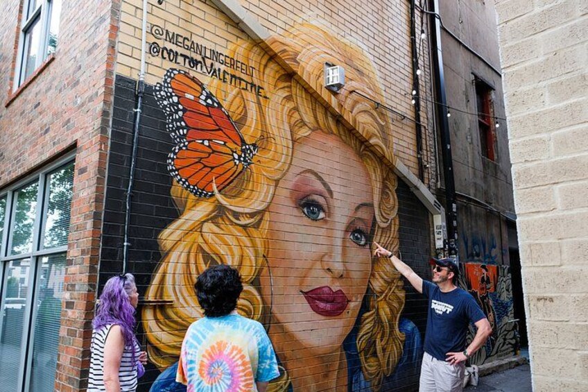 Un mural en un edificio de ladrillo con una mariposa y un retrato de mujer. 3