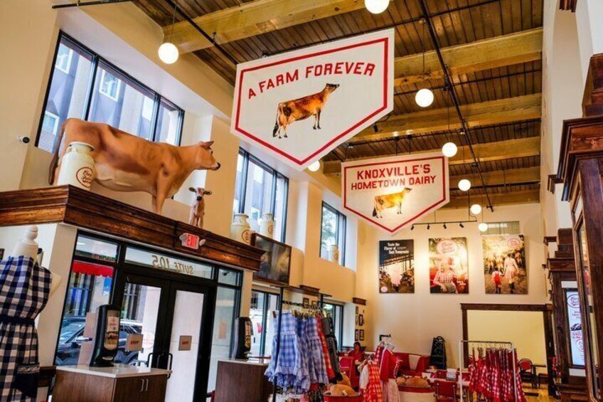 A store interior with a cow decoration, a sign reading 'A FARM FOREVER,' and 'KNOXVILLE'S HOMETOWN DAIRY.' 3