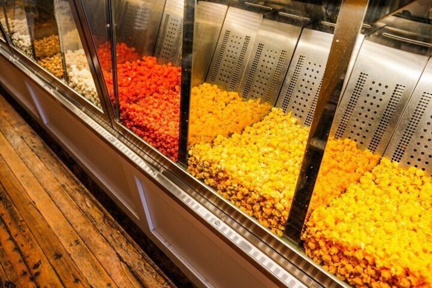 A food display with various colored toppings in a glass container. 4