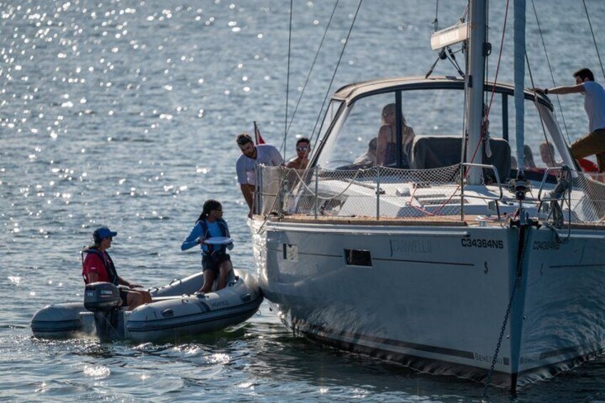 A sailboat with people on board and a smaller inflatable boat nearby. 4