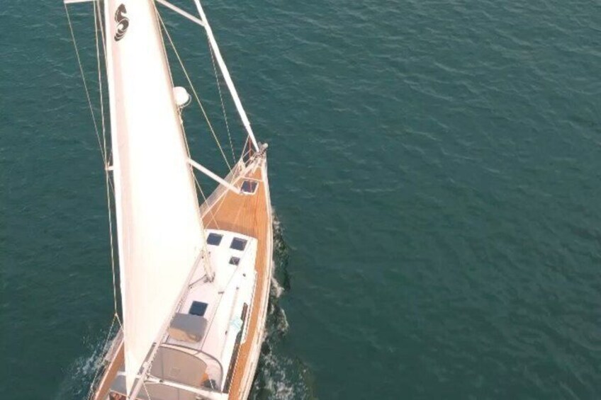 A sailboat with a white sail and a wooden deck. 1