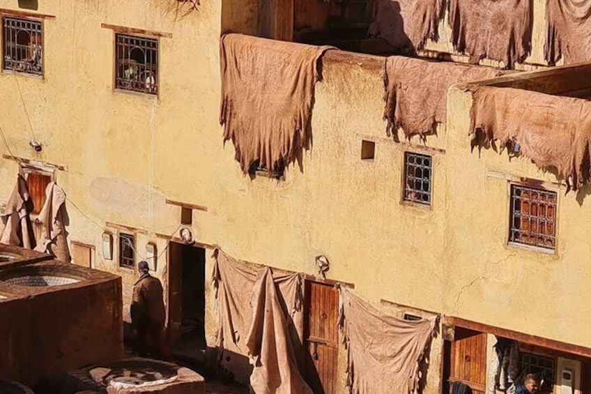 A multi-story building with hanging laundry and a traditional water well. 1
