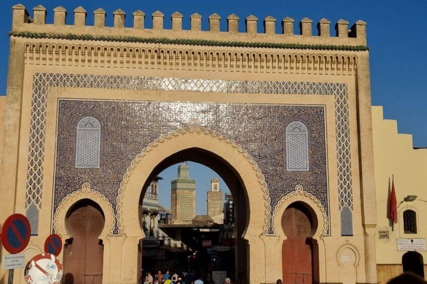 A historic archway with intricate tile work and two wooden doors. 5