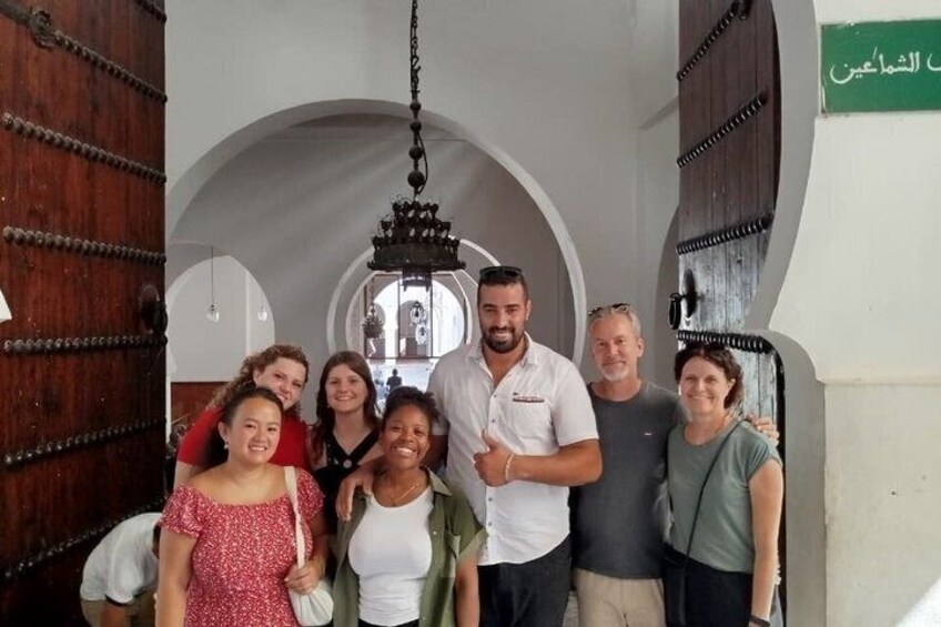 A group of people in a building with arched doorways and a chandelier. 1