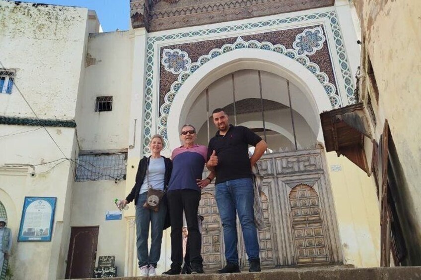 A group of people standing in front of a traditional gate with intricate tile work. 2