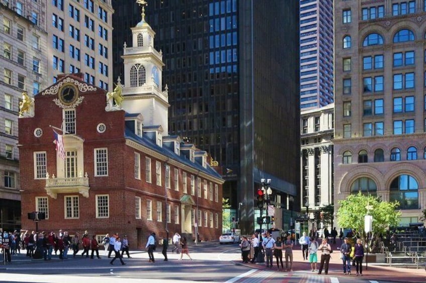 A busy urban street with pedestrians crossing, historic buildings, and a prominent clock tower. 3