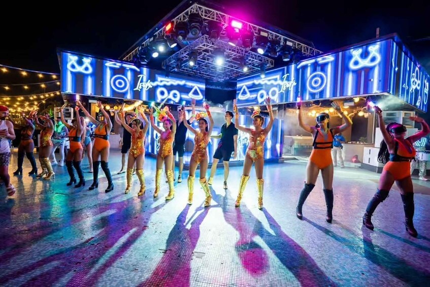 A group of dancers performing on a stage with a vibrant, illuminated backdrop. 2