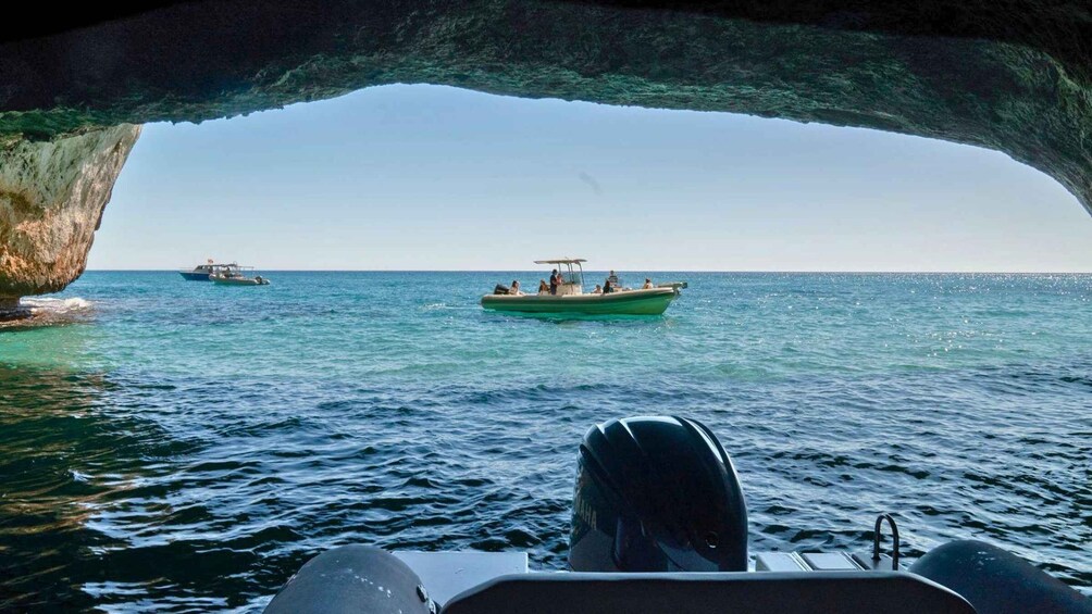 A boat in a cove with clear blue water and a rocky outcrop on the left. 4