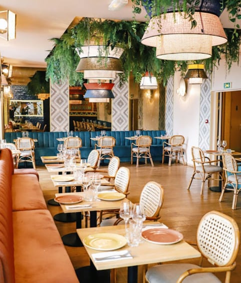 A restaurant interior with blue booths, wicker chairs, and hanging plants. 4