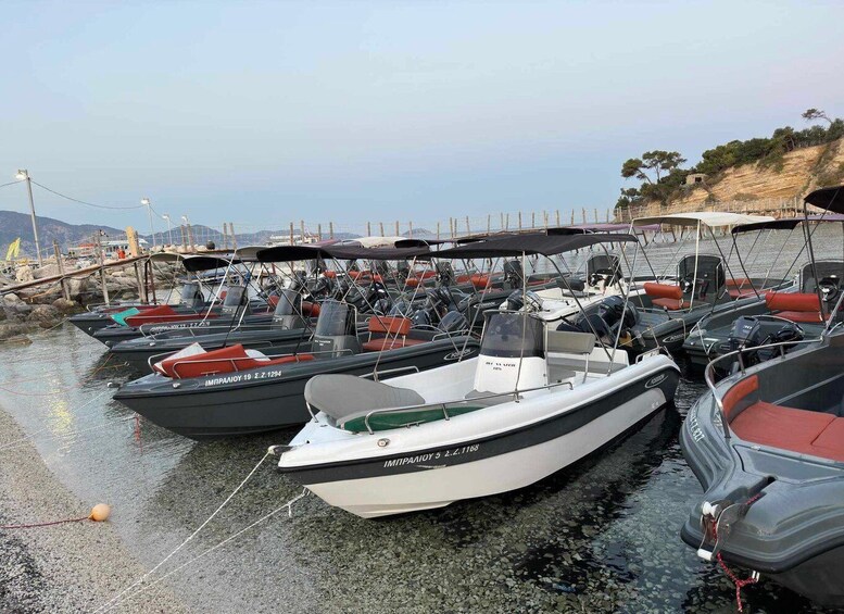 A marina with several boats docked, a rocky shoreline, and a clear sky. 5