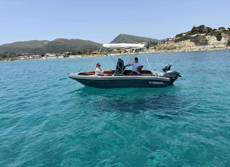 A Poseidon boat on clear turquoise water with a coastal landscape and hills in the background. 1