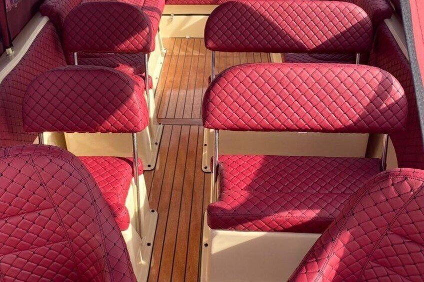 A row of red cushioned seats on a wooden deck. 4