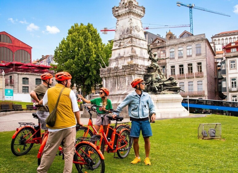 A group of people with bicycles near a historic monument and buildings. 1