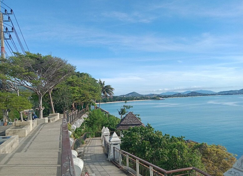 A coastal walkway with a view of the sea and distant mountains. 2