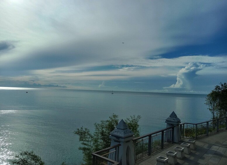 A coastal landscape with a clear view of the sea, a distant airplane, and a traditional building with a balcony. 5