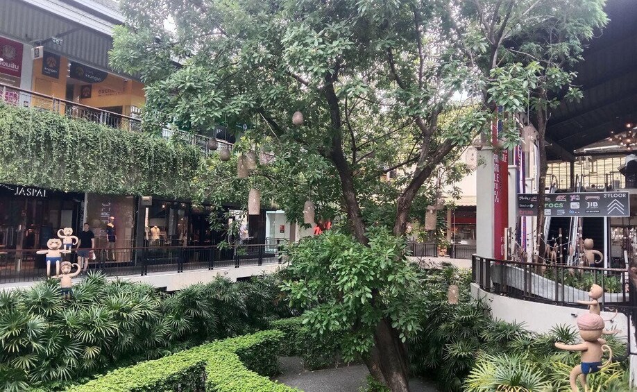 A shopping mall with a central tree, surrounded by various stores and a fenced walkway. 3