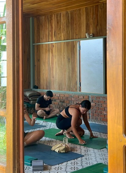 Three people practicing yoga on mats in a room with wooden walls and a window. 3